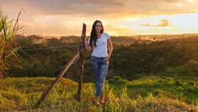 Catalina Vélez står i en solfylt eng i solnedgangen