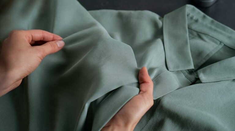 Hender som undersøker en grønn skjorte.