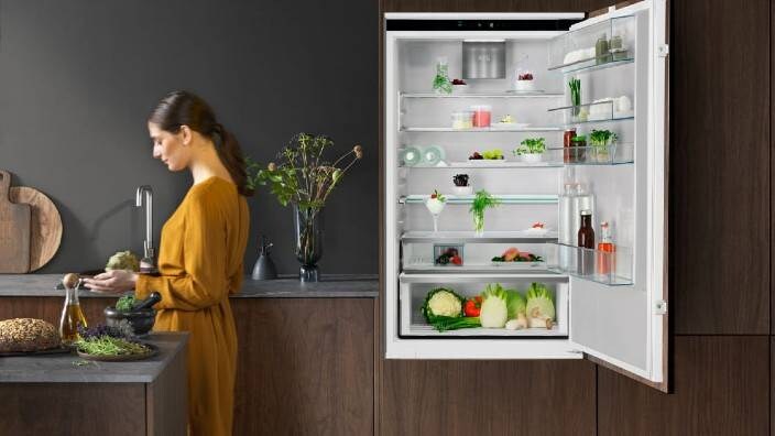 En kvinne tar ut mat fra et kjøleskap. 