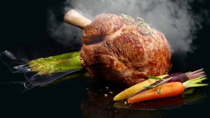 Dampet kjøtt med vakuumpakkede grønnsaker på et stekebrett.