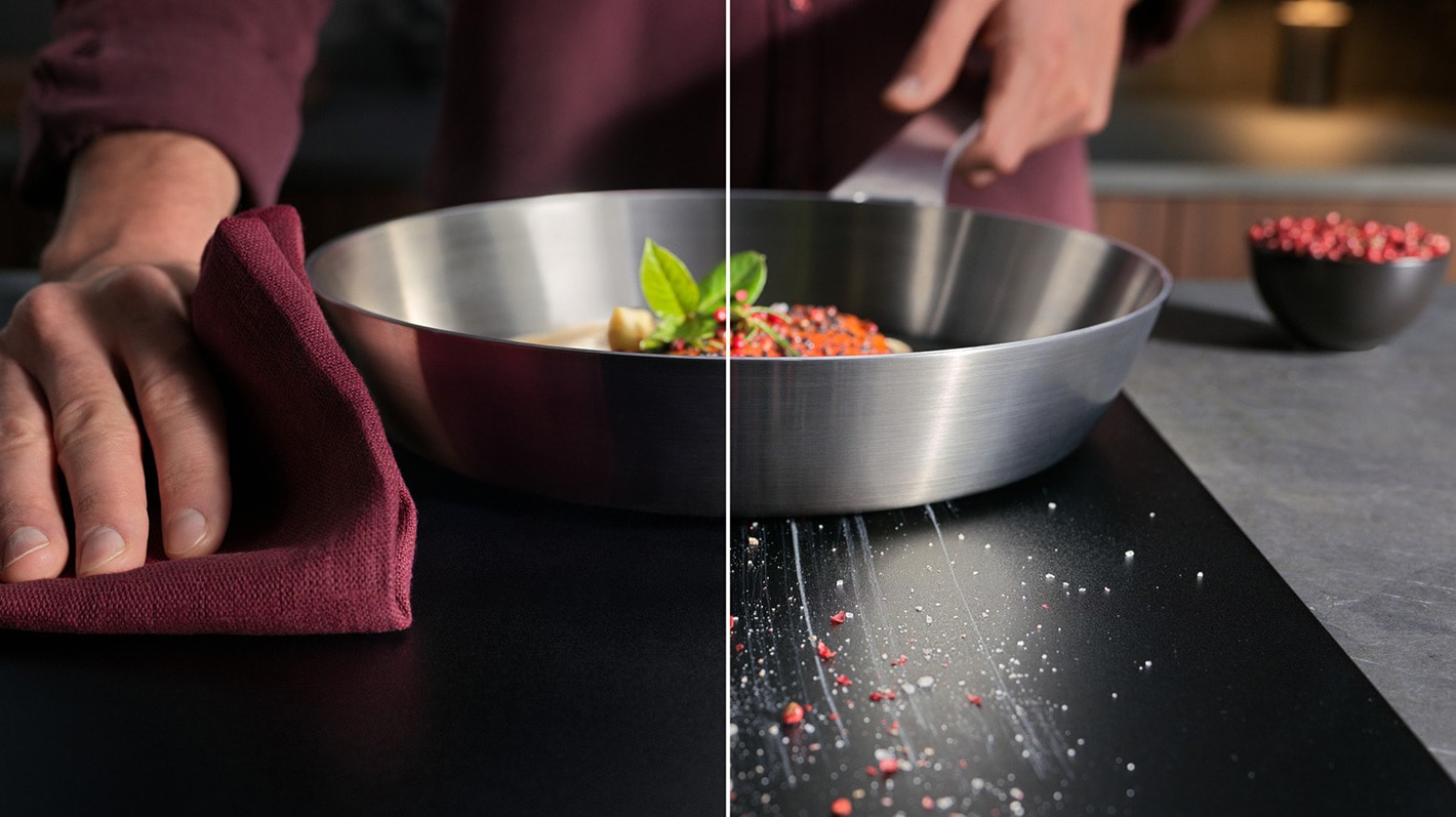 En person tørker av en induksjonstopp med en klut.