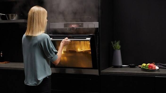 En kvinne følger med på maten som tilberedes i en dampovn.