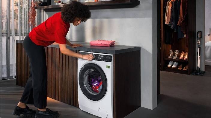 En kvinne starter en farget vask i en vaskemaskin fra AEG.