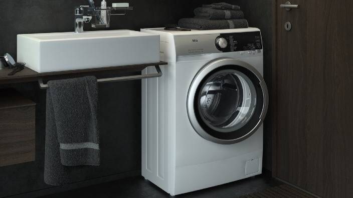 En kompakt vaskemaskin står på et lite bad.