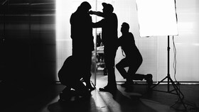 Svart hvitt bilde på folk som fikser en mann i Whyred klær før en fotografering