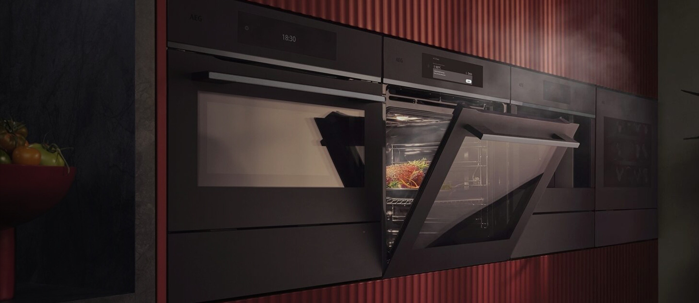 En innebygd AEG-dampovn i en moderne kjøkkenvegg med røde, riflede paneler som viser matlaging med damp